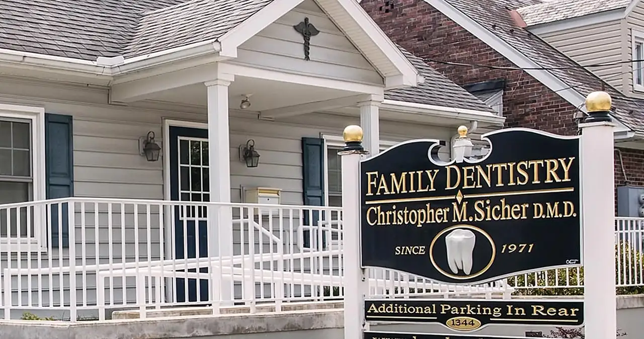 The Sicher Family Dentistry office on East Chocolate Avenue in Hershey, with its porch and the roadside sign reading Family Dentistry, Christopher M. Sicher D.M.D., since 1971.
