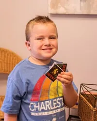 A young patient smiling and holding up his stickers at Sicher Family Dentistry.